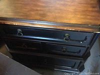Top front angle view of the dresser showing wooden top with some wear, drawers with ring pull handles