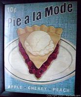 Front view photo of the framed vintage Pie a la Mode poster showing slice of cherry pie topped with ice cream. Text reads 10 cent Pie a la Mode and lists Apple, Cherry, Peach.