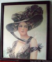 Full view of framed portrait of young woman in decorative hat, showing the entire piece including frame and artwork.