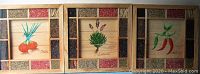 Three wooden framed kitchen pictures with spice boxes showing onions, lavender, and chilies.