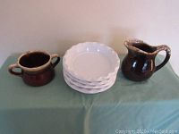 Sugar bowl, creamer, and four stacked white ovenproof bowls on green cloth background