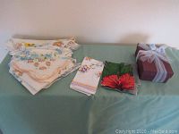 Photo showing multiple ladies handkerchiefs with floral patterns and a boxed pewter prayer box on a table.