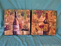 Pair of hand painted canvases showing rustic wine-themed artwork including wine bottles, glasses, grapes, and cheese on a blue cloth background.