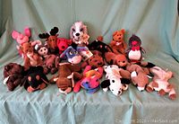 Photo showing 20 assorted Ty Beanie Babies including dog, moose, pink flamingo, penguin, orange bear, squirrel, rainbow bear and others, all with tags visible.
