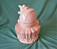 Full view of the pink ceramic clown cookie jar with lid on a fabric surface.