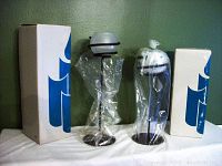 Two sets of Partylite candle holders, each set with two holders, one set unwrapped and one set wrapped in plastic, with original boxes.