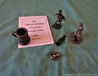 Top view of pewter statues, English tankard mug, and certificate on green cloth background.