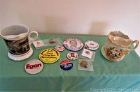 Photo showing coffee style mustache cup with black and gold historic city design and various pins laid out on table