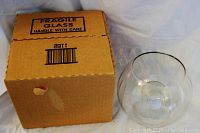 Cardboard box labeled fragile with clear round glass candle holder beside it