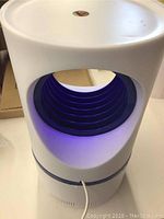 Front angle showing the white cylindrical device with blue inner vent ring and USB cable connected.