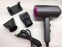Grey and purple Breeze hair dryer shown with power cord, stand, and two nozzle attachments including a comb nozzle