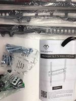 PERLESMITH medium tilt TV wall mount components including metal brackets, screws in sealed bags, and instruction manual