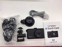 Photo of Carigaga D4 dash camera, suction mount, bracket mount, USB cable, and user manual laid out on white surface