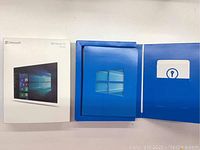 Original Microsoft Windows 10 Home retail box and blue folder with product key folder inside.