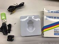 Lot contents including SQ11 Mini DV camera, mounts, charger and packaging box on white surface.