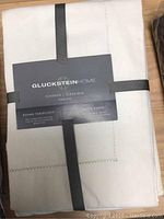 Gluckstein Home Harlow round tablecloth folded with label showing linen and cotton blend fabric