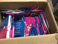 Large box filled with many individual Color in Kids marker sets, each set in packaging with brightly colored designs, mostly pink and blue.