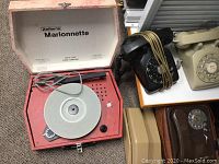Zellers Marionette record player in pink case alongside black and beige telephones