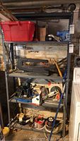 Full view of metal shelving unit with all tools and boxes included in the lot, showing Craftsman scroll saw and assorted items on multiple shelves