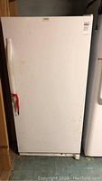 Full front view of the white Kenmore freezer with visible stains and a red piece of tape on the handle.