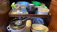 Photo of kitchen drawers filled with various bowls, colanders, measuring cups, a chopper, and shakers.