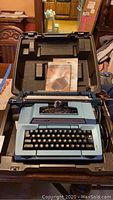 Blue Smith Corona typewriter with keyboard inside hard carrying case, manual included.