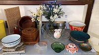 Overall view of lot including serving bowls, vases with faux flowers, coasters and small dishes on a table.