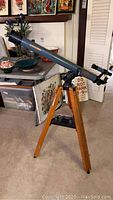 Full view of blue Cometron DCO60 refractor telescope mounted on wooden tripod indoors