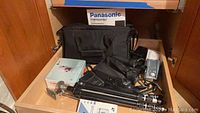 View showing Panasonic Palmcorder IQ box, black camera carrying case and accessories in drawer