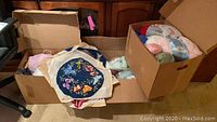 Three boxes filled with yarn skeins and a floral needlepoint canvas