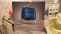 Front of the box showing model 7135 humidifier with blue transparent water tank and white base