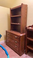 Full view of wood dresser with bookshelf on top showing wood grain and drawer hardware