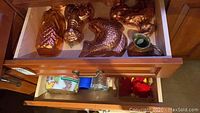 Top view of drawer showing multiple copper molds in various animal and fruit shapes, plus some cookie cutters and cookie press parts.