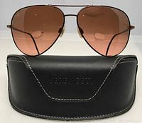 Front view of Serengeti Bordeaux aviator sunglasses resting on the branded hard case showing brown gradient lenses and thin frame design.