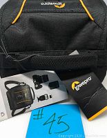 Top partial view focusing on Lowepro branding, black color and orange details on the exterior with manuals and tags laid out in front.