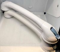Two white flexible suction bathroom safety rails with grey locking levers, laid on a white surface.