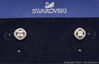 Front view of Swarovski earrings showing the square central crystal surrounded by a circle of smaller pave crystals on dark blue Swarovski display card.