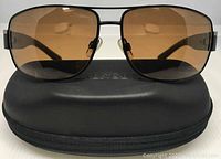 Frontal view of the Serengeti Monte sunglasses with brown lenses positioned on top of the black zippered case.