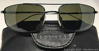 Front view of the Serengeti San Remo sunglasses resting on the Serengeti branded black case showing green polarized lenses and rectangular frame.