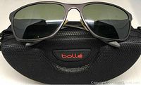 Front view of Bolle sunglasses on top of Bolle branded hard case.