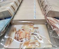 Three shrink-wrapped packages, each containing 12 boxes of Elie Saab Le Parfum 1 ml bottles, visible packaging and brochure showing the perfume bottle.