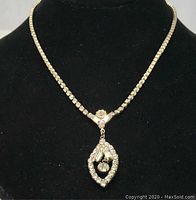 Front view of the crystal necklace on a black display bust, showing charm pendant and chain.