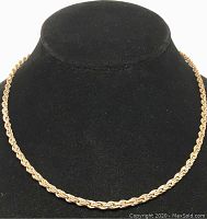 Front view of the gold and silver twist link chain necklace displayed on a black jewelry bust.