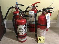 Five red dry chemical fire extinguishers grouped together, showing labels and hoses