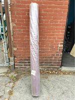 Full view of the fabric roll standing upright against a brick wall, wrapped in clear plastic with label number 401 visible.