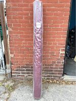 Full length view of the fabric roll wrapped in plastic against a brick wall.