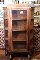 Front view of the solid oak curved glass curio cabinet with rounded breakfront and four shelves inside.