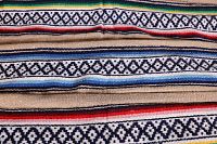 Close-up of woven Southwest style pattern with geometric diamonds on beige with red, blue, green, yellow stripes.