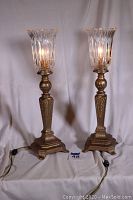 Full view of both lamps showing painted iron bases and crystal glass shades illuminated.