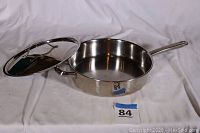 Fry pan with matching lid placed on a white cloth background, showing overall condition and size.